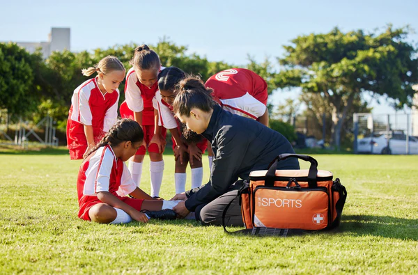 Sports Team looking and a first aider putting a bandage on an injured player